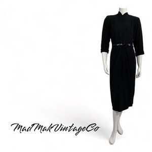 May include: A black vintage dress with a mandarin collar and a black belt. The dress has a fitted bodice and a flowing skirt.