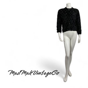 May include: A black sparkly sweater with a zip closure. The sweater is on a white mannequin.
