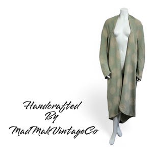 May include: A long, green and white patterned cardigan with a shawl collar. The cardigan is made of a soft, lightweight fabric and has a relaxed fit. Handcrafted by Mad Mak Vintage Co.