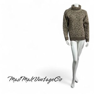 May include: A brown and beige patterned turtleneck sweater. The sweater has a geometric design and is displayed on a mannequin. The sleeves and hem are a darker brown. The Mad Mak Vintage Co logo is in the bottom left corner.