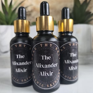 May include: Three glass bottles with gold caps and black labels. The labels say "The Alixander Alixir" and "Healthy Skin".