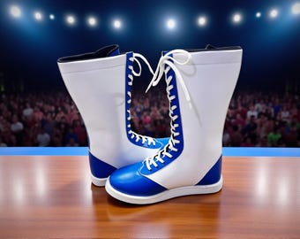 May include: A pair of white and blue wrestling boots with white laces. The boots have a high-top design with blue accents on the toe, heel, and side panels. The boots are displayed on a wooden surface.