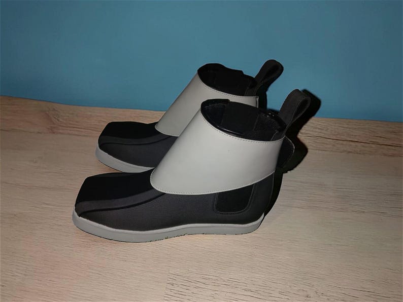 Peut inclure: Une paire de bottines noires et grises au design unique. Les bottines pr&eacute;sentent une bande grise autour de la cheville et une tirette &agrave; l'arri&egrave;re. Les semelles sont grises et les bottines semblent &ecirc;tre faites d'une mati&egrave;re souple.