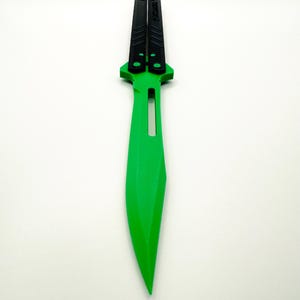 May include: A green butterfly knife with black handles. The handles have the word "UNSTOPPABLE" printed on them.