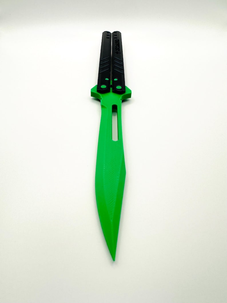 May include: A green butterfly knife with black handles. The handles have the word "UNSTOPPABLE" printed on them.