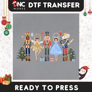 May include: A DTF transfer sheet featuring a festive illustration of two nutcrackers, a fairy in a gold dress, a dancer in a blue dress, and a mouse king. The design includes two Christmas trees, wrapped gifts, and hanging ornaments.