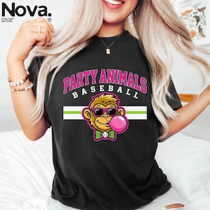 May include: Black t-shirt with the text "PARTY ANIMALS BASEBALL" in pink and white. The shirt features a cartoon monkey wearing sunglasses and blowing a bubblegum bubble. The monkey has a green bow tie.