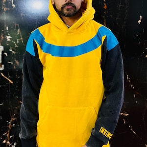 May include: Yellow hoodie with a blue stripe across the chest and black sleeves. The word "INVINC" is printed in yellow on the left sleeve. The hoodie has a front pocket and a hood.