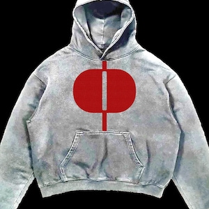 May include: A gray hoodie with a red oval and vertical line design on the front. The hoodie has a hood, a front pocket, and red cuffs. The background is black.