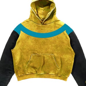 May include: Mustard yellow hoodie with a teal blue curved stripe across the chest. The hoodie has black sleeves and a front pocket. The hood is lined with the same mustard yellow material. The fabric has a textured, worn appearance.
