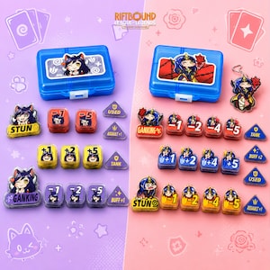 May include: A Riftbound League-Legends trading card game set featuring two blue plastic storage cases, acrylic character charms, and various game tokens. The tokens include numerical values, status effects like Stun and Ganking, and buff markers.