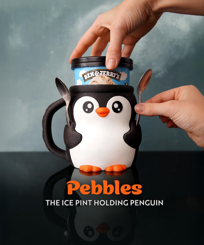A black penguin ice cream holder with an ice cream pint inside and two spoons
