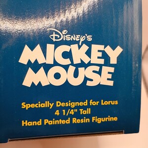 Puede incluir: Caja azul con el logotipo de Disney's Mickey Mouse en blanco. El texto debajo dice: "Especialmente dise&ntilde;ado para Lorus 10.8 cm de alto Figura de resina pintada a mano."