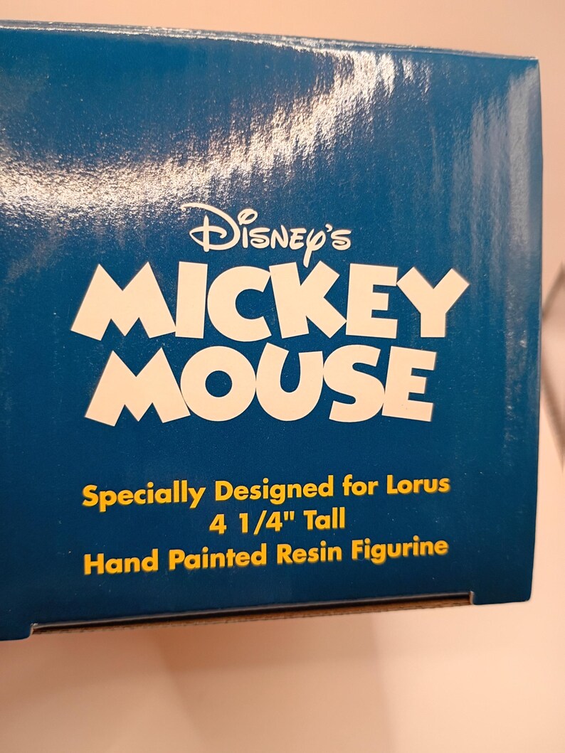 Puede incluir: Caja azul con el logotipo de Disney's Mickey Mouse en blanco. El texto debajo dice: "Especialmente dise&ntilde;ado para Lorus 10.8 cm de alto Figura de resina pintada a mano."