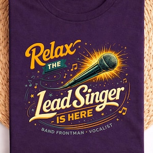 May include: A Blackberry purple t-shirt with the text "Relax the Lead Singer is Here". The graphic features a microphone with a yellow burst, musical notes, and the words "Band Frontman - Vocalist".