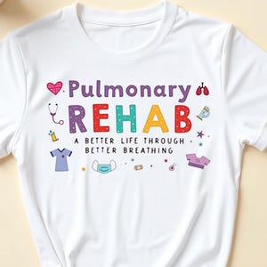 Pode incluir: Camiseta branca com o texto "Pulmonary Rehab" em letras coloridas. O texto é rodeado por pequenos ícones coloridos relacionados à saúde respiratória. O texto abaixo do texto principal diz "Uma vida melhor através de uma melhor respiração."