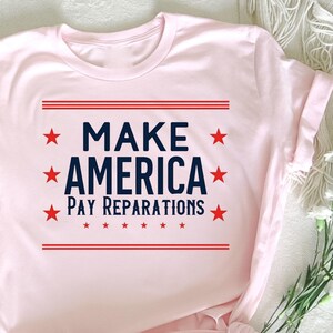 Puede incluir: Camiseta rosa con el texto "Make America Pay Reparations" en letras azules con estrellas rojas.