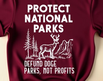 Puede incluir: Una camiseta de color granate con un diseño gráfico blanco que dice "Proteger los parques nacionales" y "Financiar los parques, no las ganancias". El gráfico también incluye un ciervo y árboles.