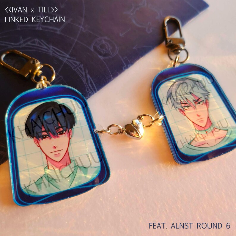 Puede incluir: Llavero enlazado con dos retratos estilo anime, unidos por una cadena con un dije de coraz&oacute;n. Cada llavero tiene un borde azul y un cierre dorado. El texto "<<IVAN x TILL>> LINKED KEYCHAIN" es visible.