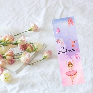 Peut inclure: Un marque-page rose et violet avec une illustration de ballerine, un papillon et le nom "Léna".