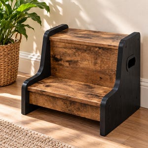 May include: A two-step stool featuring a rustic brown wood-grain finish on the treads and risers, contrasted by solid black side panels. The side panels include integrated cutout handles for portability and a sturdy, low-profile design.