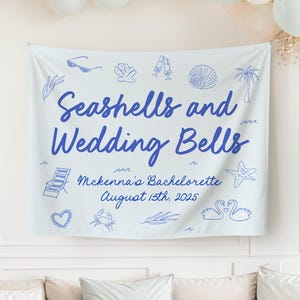 Pode incluir: Uma faixa azul clara com o texto "Seashells and Wedding Bells" em escrita azul. A faixa inclui ilustrações de óculos de sol, conchas, taças de champanhe, uma concha, uma palmeira, uma cadeira de praia, um coração, um caranguejo, uma estrela do mar e cisnes. O texto "Mckenna's Bachelorette August 13th, 2025" também está incluído.