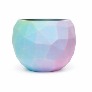 May include: A round, geometric planter with a pastel color scheme. The planter's surface is divided into numerous triangular facets, creating a textured appearance. The colors transition from blue to pink, with a hint of green.