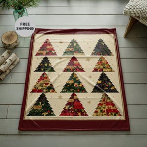 May include: A rectangular throw blanket with a cream-coloured background and a deep red border. The blanket features a repeating pattern of twelve stylised Christmas trees arranged in four rows, each decorated with various floral and botanical prints.