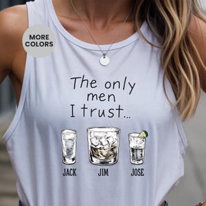 Puede incluir: Una camiseta sin mangas azul claro con el texto "The only men I trust..." e ilustraciones de tres cócteles diferentes. Los nombres "JACK", "JIM" y "JOSE" están impresos debajo de cada bebida.