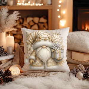 May include: A white cushion with a festive gnome design. The gnome is adorned in gold-coloured trim and holds a gift. The cushion has a soft, textured look, ideal for seasonal home decoration.