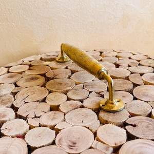 May include: A wooden table top made of many small, round pieces of wood. The table top has a brass handle with an ornate design.