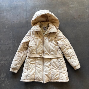Puede incluir: Abrigo de invierno acolchado beige con capucha y cinturón. El abrigo tiene cierre de cremallera y puños de canalé. Las costuras son de un tono beige más oscuro, creando un diseño contrastante. El abrigo está diseñado para el clima frío.