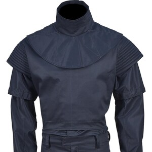 Puede incluir: Una camisa de color azul oscuro con cuello alto y un dise&ntilde;o &uacute;nico en los hombros. La camisa tiene manga larga y un estilo ajustado.