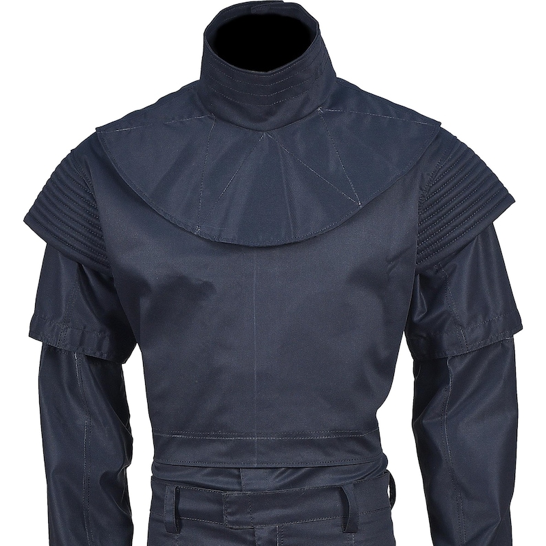 Puede incluir: Una camisa de color azul oscuro con cuello alto y un dise&ntilde;o &uacute;nico en los hombros. La camisa tiene manga larga y un estilo ajustado.