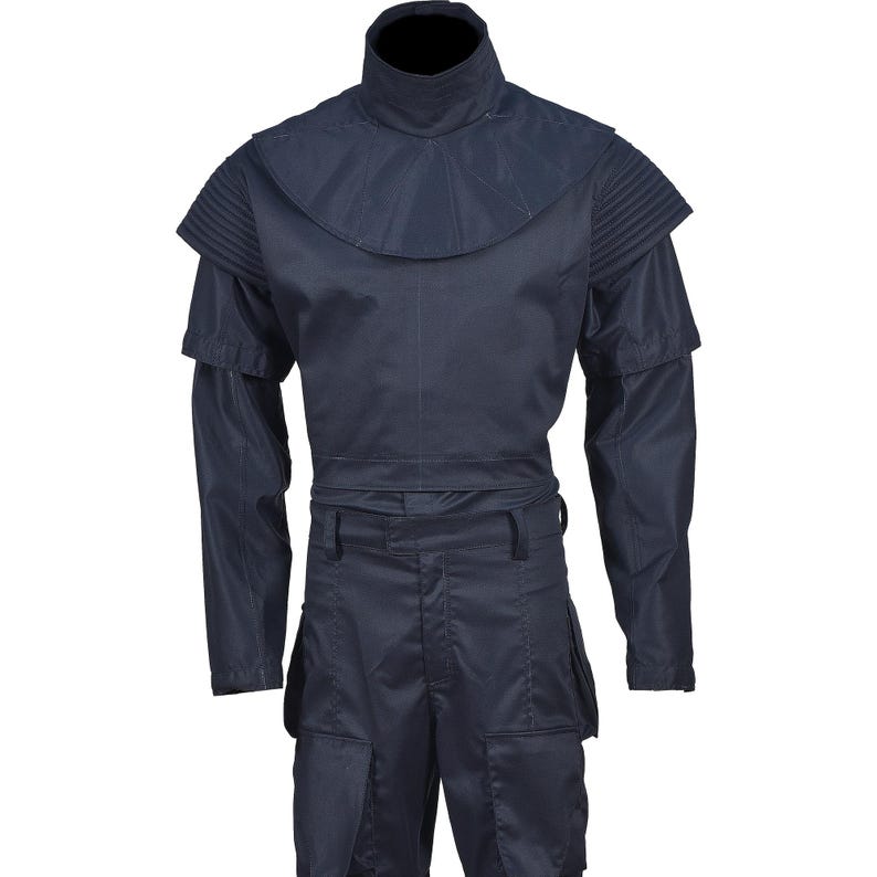 Puede incluir: Un mono azul oscuro con cuello alto y mangas largas. El mono tiene un cintur&oacute;n y bolsillos cargo.