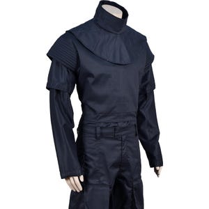 Puede incluir: Un mono azul oscuro con cuello alto y mangas largas. El mono tiene un cintur&oacute;n y bolsillos.