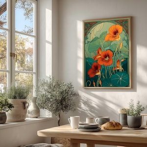 K&ouml;nnte beinhalten: Ein gerahmter Kunstdruck mit stilisierten orangefarbenen Kapuzinerkressebl&uuml;ten und gr&uuml;nen Bl&auml;ttern. Das Kunstwerk hat eine Vintage-&Auml;sthetik mit einem goldenen Rahmen und einem gr&uuml;nen und orangefarbenen Rand. Der Druck wird an einer wei&szlig;en Wand in einem hellen Raum angezeigt.