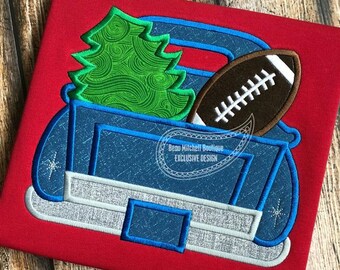 May include: A blue truck bed design with a green Christmas tree and a brown football. The design is on a red background. The text "Beau Mitchell Boutique EXCLUSIVE DESIGN" is in the lower right corner.