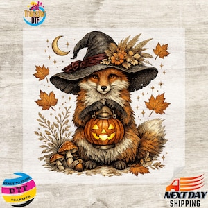 May include: A graphic print featuring a fox wearing a dark witch hat adorned with orange flowers and wheat. The fox holds a glowing jack-o'-lantern lantern. The scene includes falling autumn leaves, small mushrooms, and a crescent moon.