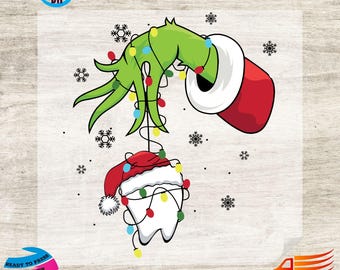 以下が含まれることがあります： クリスマスライトで飾られた緑の手が、サンタ帽をかぶった歯を持っています。歯はクリスマスライトで飾られています。デザインには雪の結晶が含まれており、DTF転写です。
