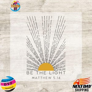 May include: A digital transfer design featuring a black and white sunburst with a yellow sun in the center. The text "BE THE LIGHT" and "MATTHEW 5:14" is below the sun.