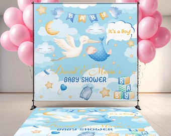 May include: A baby shower backdrop and floor decal set with a blue sky theme, featuring a stork carrying a baby, clouds, and stars. The backdrop reads "Baby Shower" and "It's a Boy!" with pink balloons in the background.