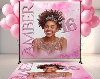May include: A pink Sweet 16 backdrop and floor decal featuring a smiling young woman wearing a crown. The backdrop has the name "Amber" and the number "16" in glittery pink. Pink balloons are on either side.