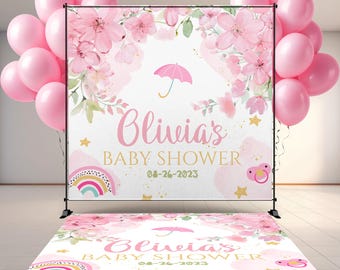 May include: A baby shower backdrop and floor decal set with a pink floral design, a rainbow, and the text "Olivia's BABY SHOWER 08-26-2023". Pink balloons are arranged on the left and right sides of the backdrop.