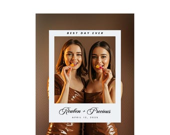 May include: A framed photo featuring two women smiling and holding lollipops. The photo has the text "Best Day Ever" at the top and "Reuben + Precious, April 12, 2025" at the bottom. The women are wearing brown outfits.
