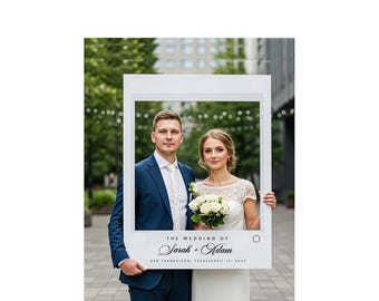 May include: A white photo frame with the text "THE WEDDING OF Sarah + Adam" and the date "San Francisco, February 12, 2023". A couple poses inside the frame, the man in a blue suit and the woman in a white dress.