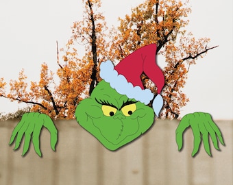May include: A green cartoon character wearing a red Santa hat with white trim, peeking over a wooden fence. The character has yellow eyes and a grumpy expression. Green hands extend from the sides.