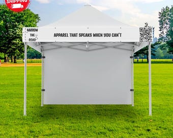 May include: A white pop-up canopy tent featuring a custom banner with the text "NARROW THE ROAD" and "APPAREL THAT SPEAKS WHEN YOU CAN'T" printed in black, along with a QR code on the right side of the valance frame structure.