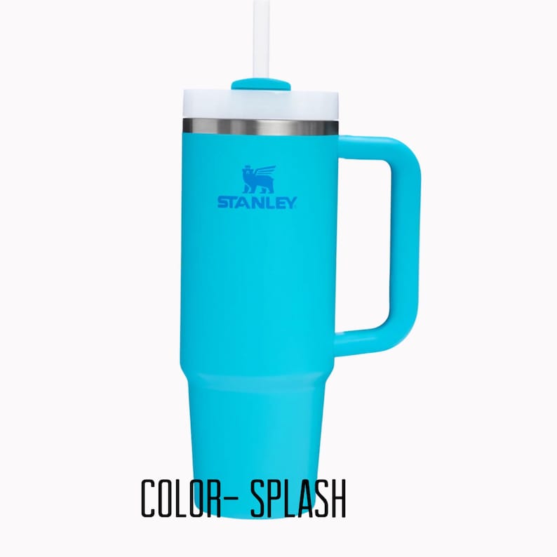 Pu&ograve; includere: Un bicchiere Stanley turchese con manico e coperchio bianco. Il bicchiere ha una cannuccia e il logo Stanley in blu. Il testo "COLOR- SPLASH" &egrave; nella parte inferiore dell'immagine.