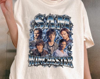 May include: An off-white short-sleeve t-shirt featuring a graphic print of Sam Winchester from the television show Supernatural. The design includes multiple images of the character surrounded by blue lightning and the text SAM WINCHESTER.